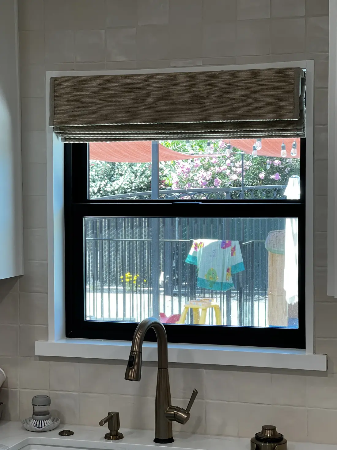 Woven wood shade fitted above the kitchen sink window in a Lodi home, stacked clear of the glass so the whole opening stays usable