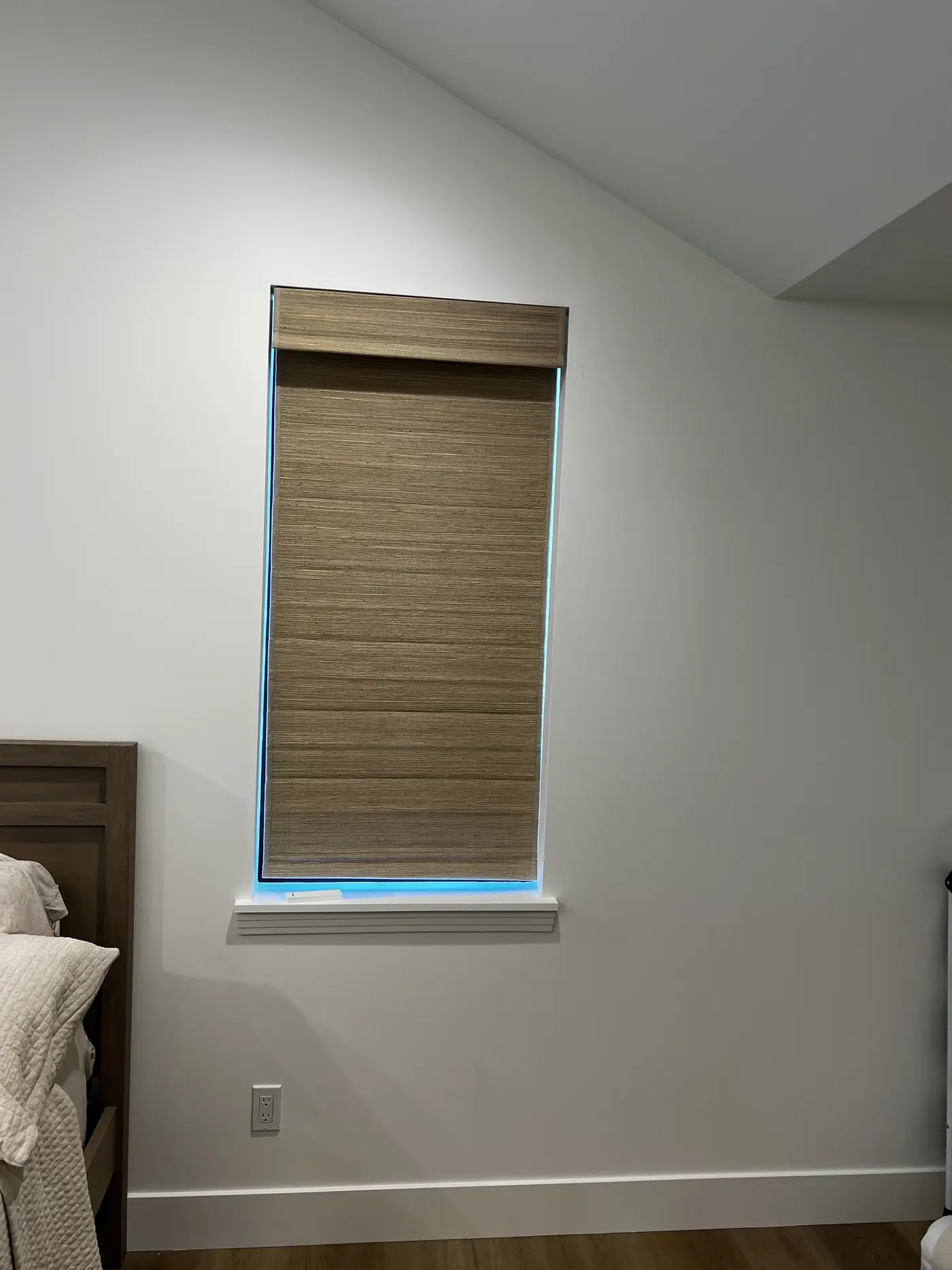 Woven wood roller shade fitted to a bedroom window in a Lodi home, lowered to the sill against a plain white wall