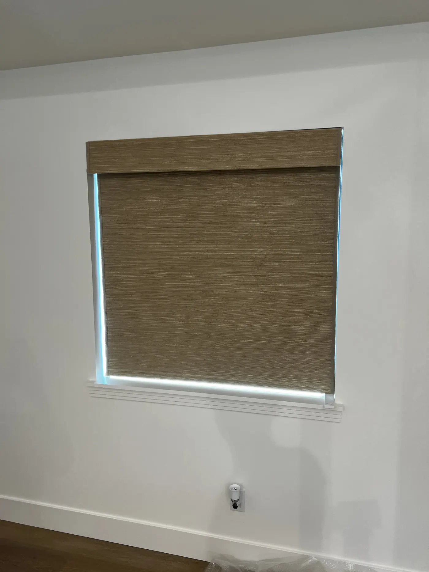Woven wood roller shade lowered across a window in a bright Lodi room, with the headrail set inside the opening