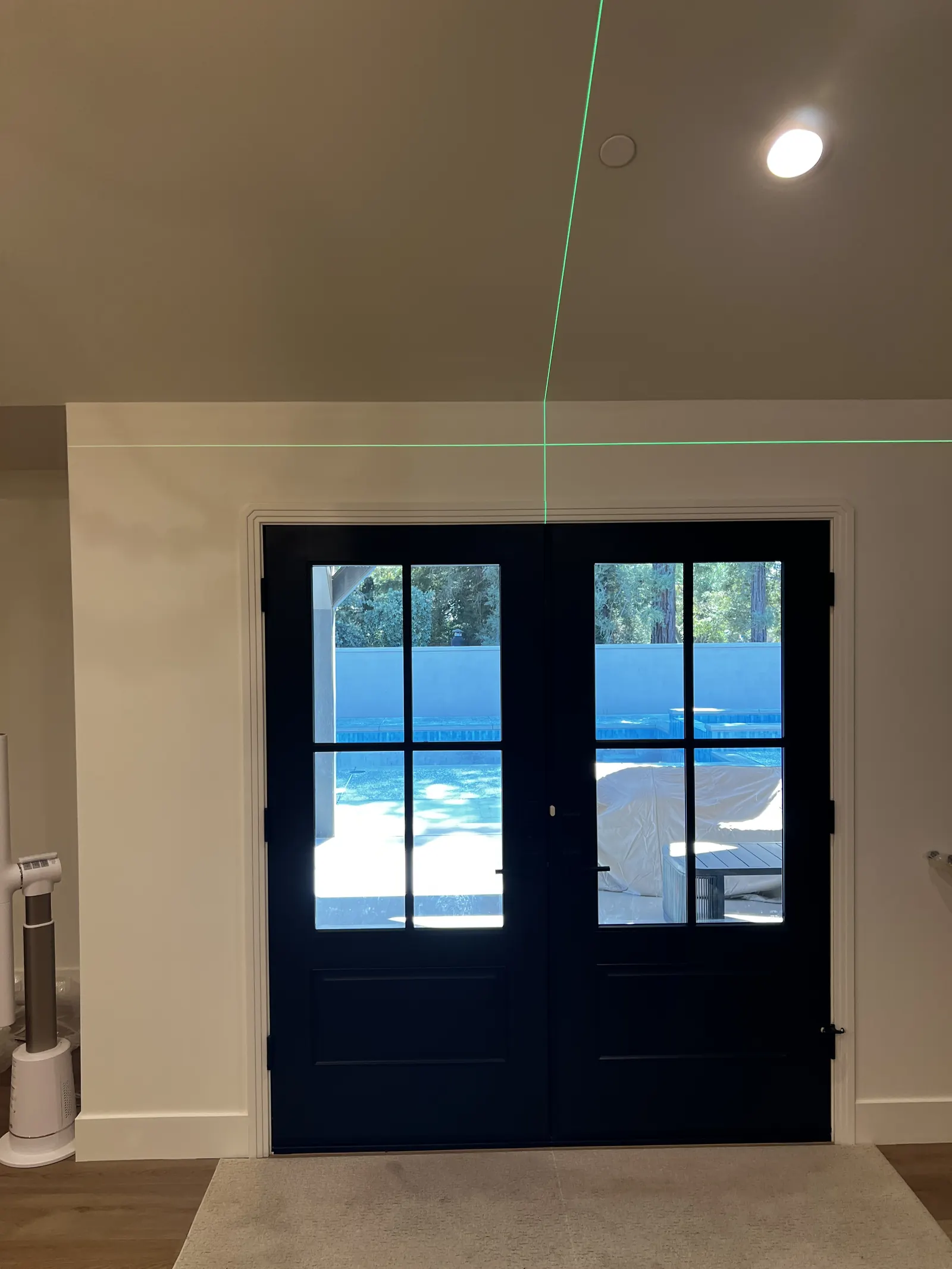 Setting the height above a pair of glazed garden doors in Lodi, the laser line running level across the wall before the rod goes up