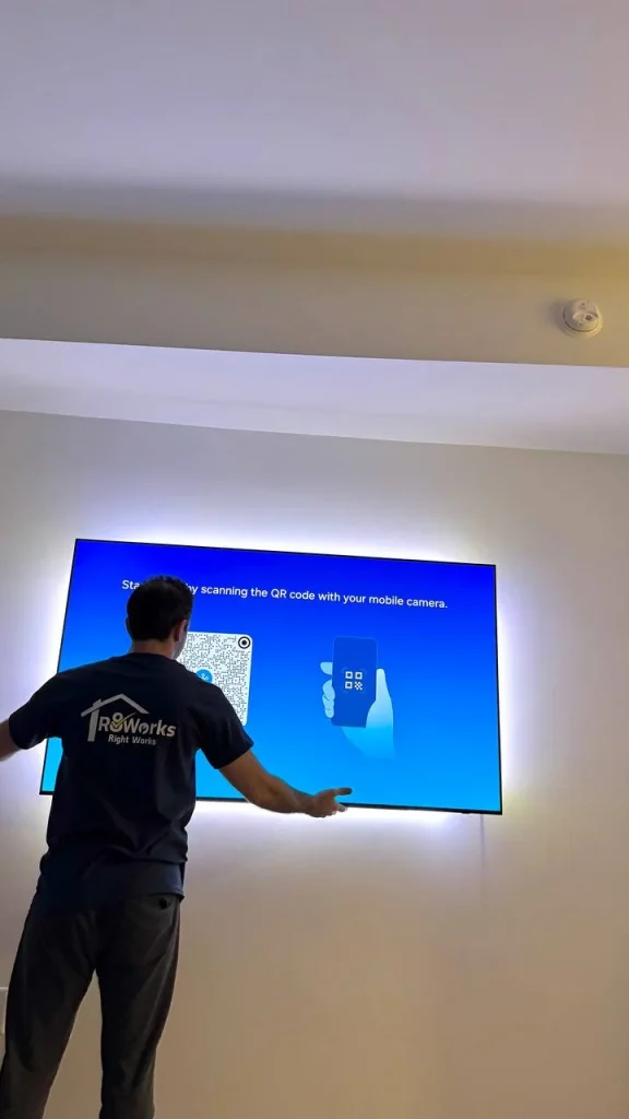 Flat screen TV mounting completed on a white wall in a San Francisco home, featuring LED backlighting around the display during final setup.